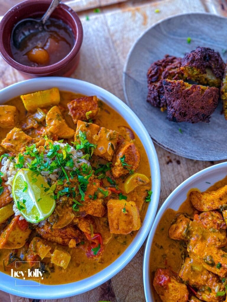 Bowl of creamy chicken tofu tikka masala served with crispy onion bhajis and brown rice