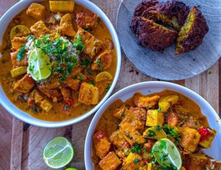 Bowl of creamy chicken and tofu tikka masala served with crispy onion bhajis and brown rice