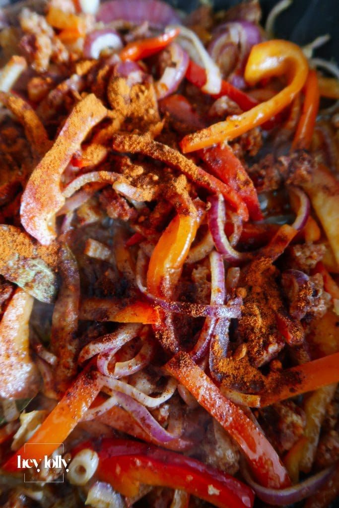 Veg base for baked cod with chorizo with tomatoes, peppers, onion and lemon. Close up of spices