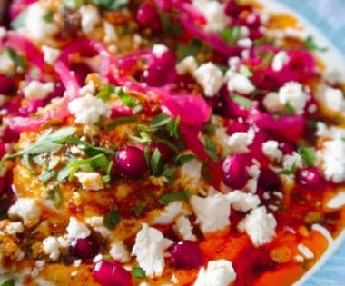 Bowl of Turkish eggs topped with spiced butter, pomegranate, feta and herbs
