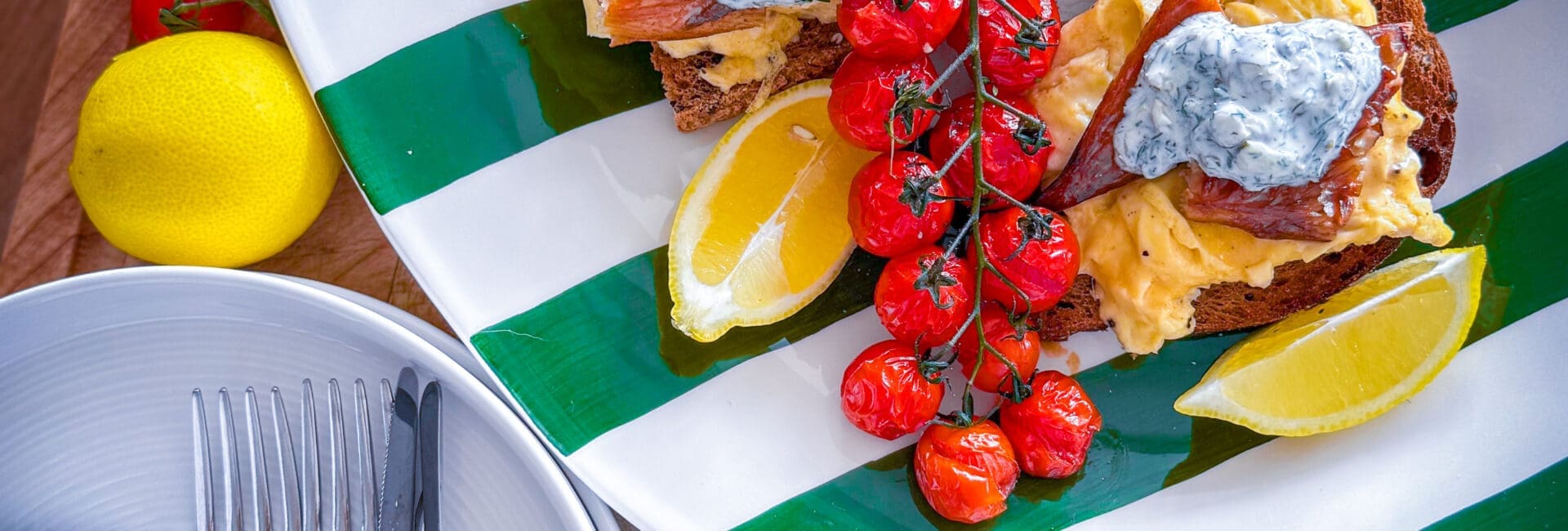 Scandi-style breakfast with eggs, mackerel, tomatoes, and crème fraîche on sourdough.