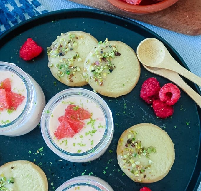Silky grapefruit posset in glass ramekin with pistachio shortbread on the side