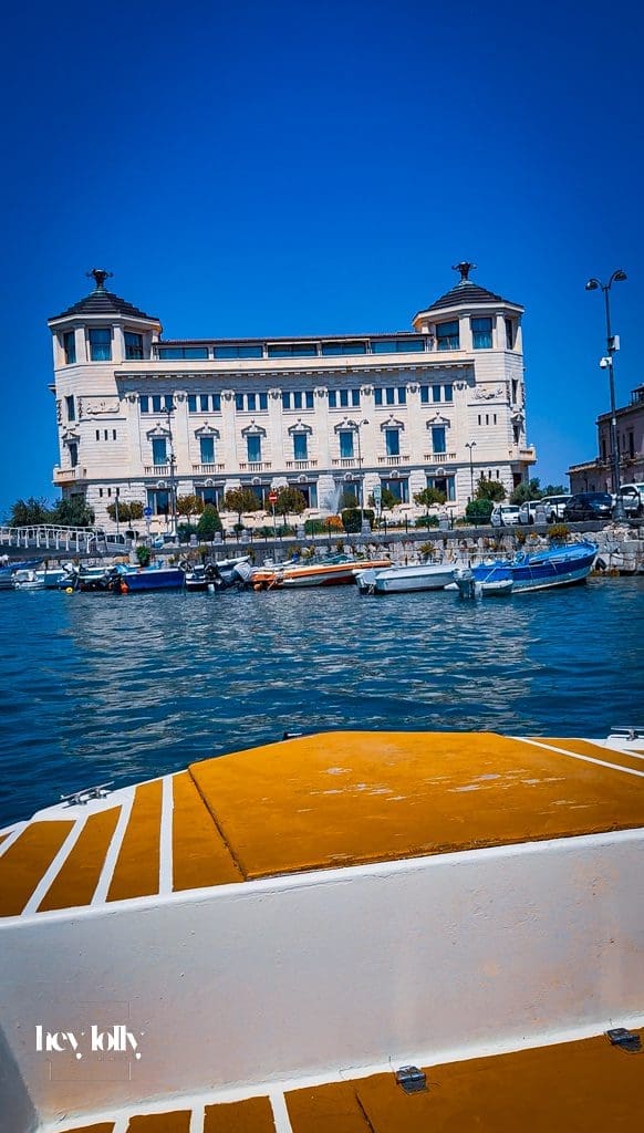Small boat passing Ortigia’s sea walls and entering a rocky cave on a tour