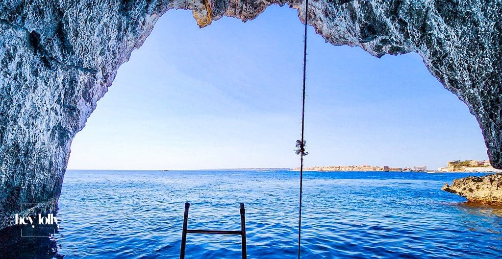 Small boat passing Ortigia’s sea walls and entering a rocky cave on a tour