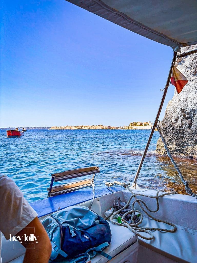 Small boat passing Ortigia’s sea walls and entering a rocky cave on a tour