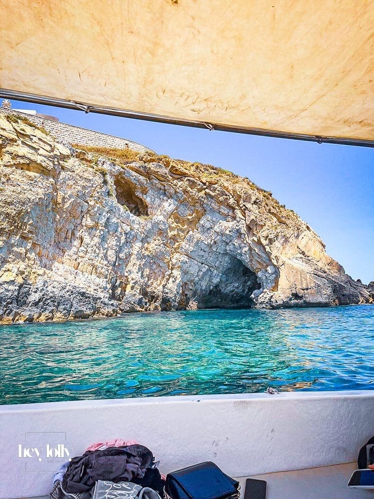 Small boat passing Ortigia’s sea walls and entering a rocky cave on a tour