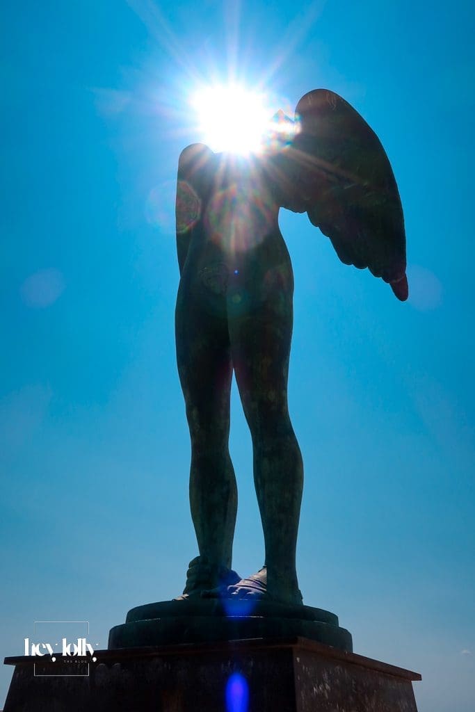 Monumental bronze statue of Ikaria with wings against the sea in Ortigia