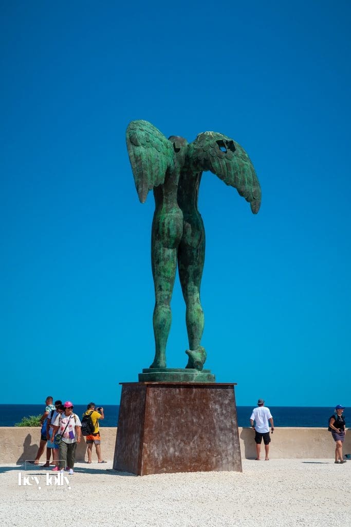 Monumental bronze statue of Ikaria with wings against the sea in Ortigia