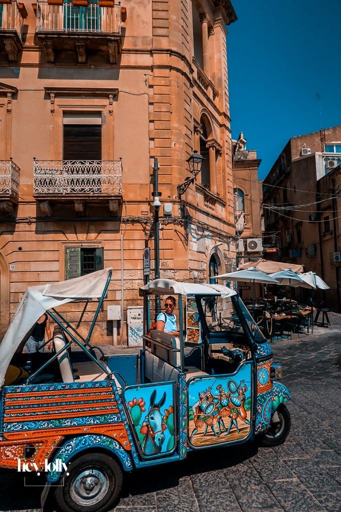 Colourful tuk tuk driving through narrow streets in Ortigia Sicily