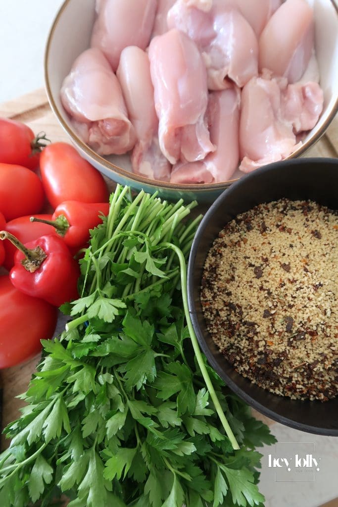 Za’atar Chicken Thighs mise en place with cherry tomatoes, anchovies, chilli, and herbs arranged on board