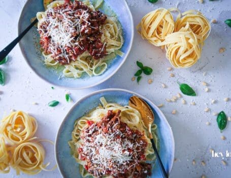 rich beef ragu plated in bowls with tagliatelle and freshly shaved parmesan
