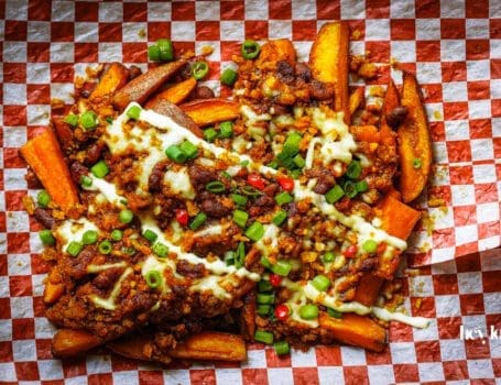 loaded sweet potato fries with sour cream and herbs, ready to share.