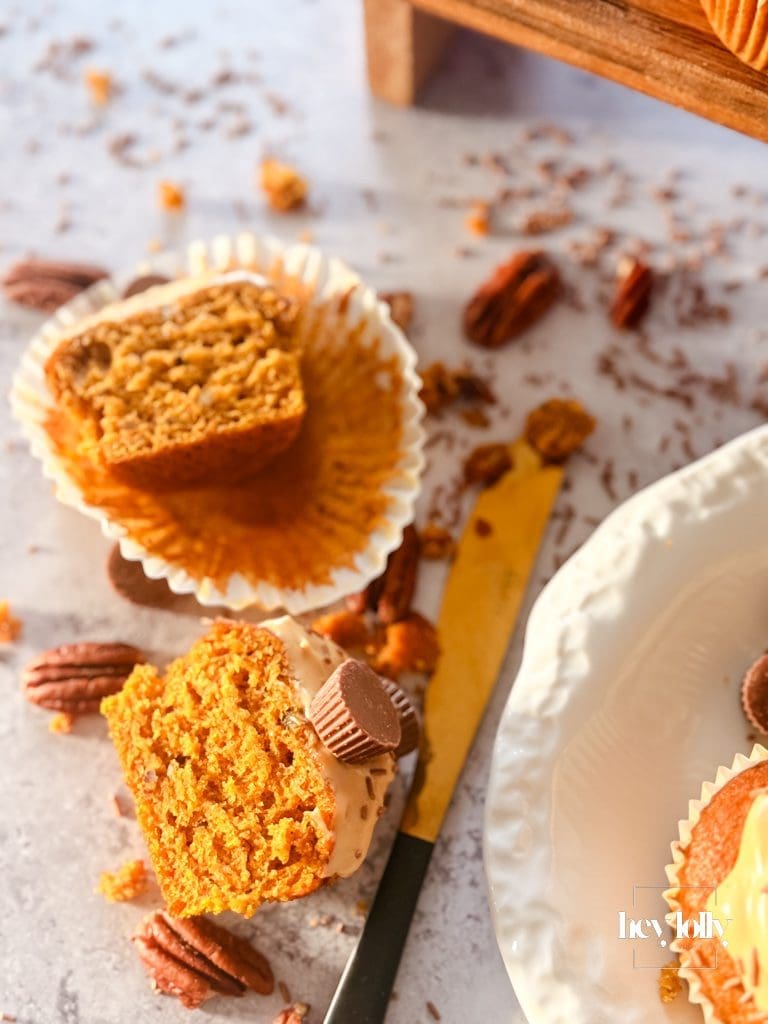 Bite shot: Pumpkin, Maple & Pecan Muffin showing soft orange crumb, pecan edge, frosting swirl.