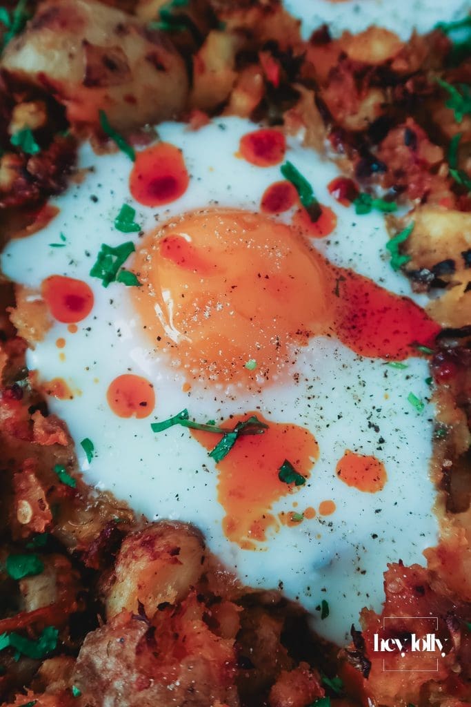 Runny egg yolk over sprout and harissa potato hash with crisp potatoes