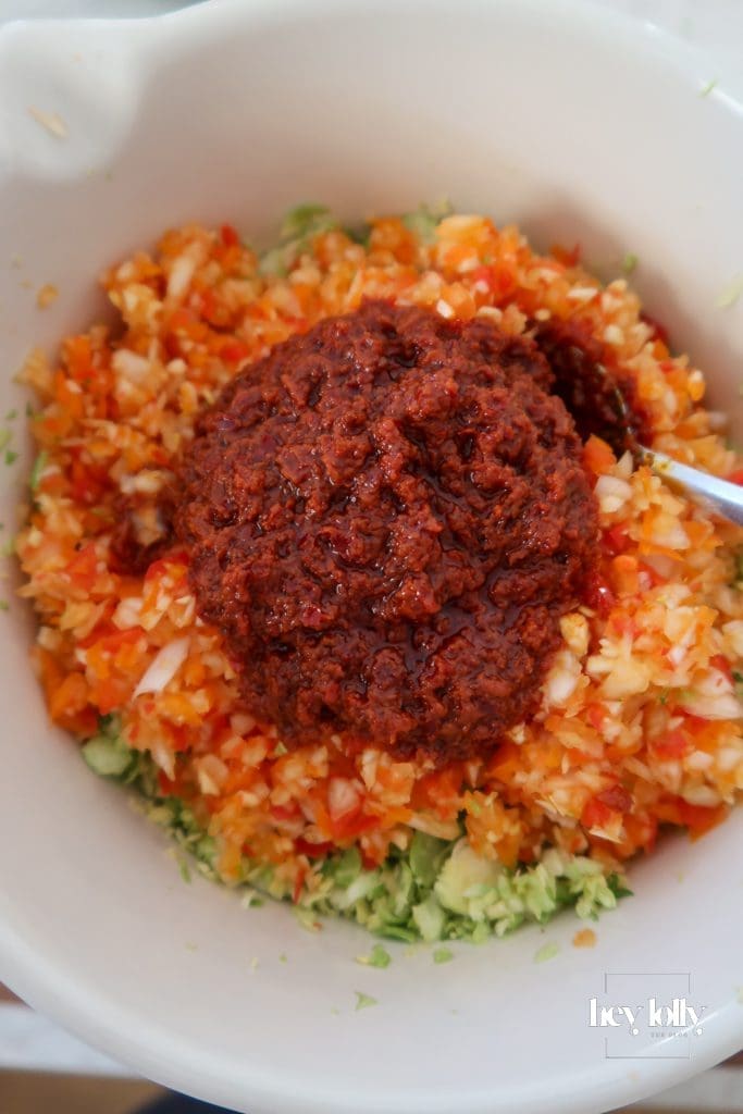 Harissa being stirred through potatoes and sprouts for a spiced breakfast hash