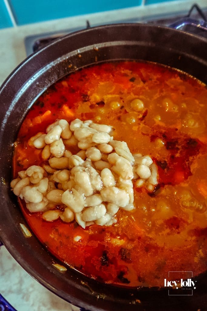 White beans and grated cheese being folded into pearl barley stew for extra creaminess
