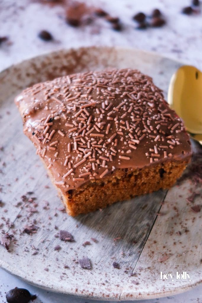 Slice of pecan and coffee cake on a plate, showing the tender crumb and shiny mocha glaze with pecan topping.
