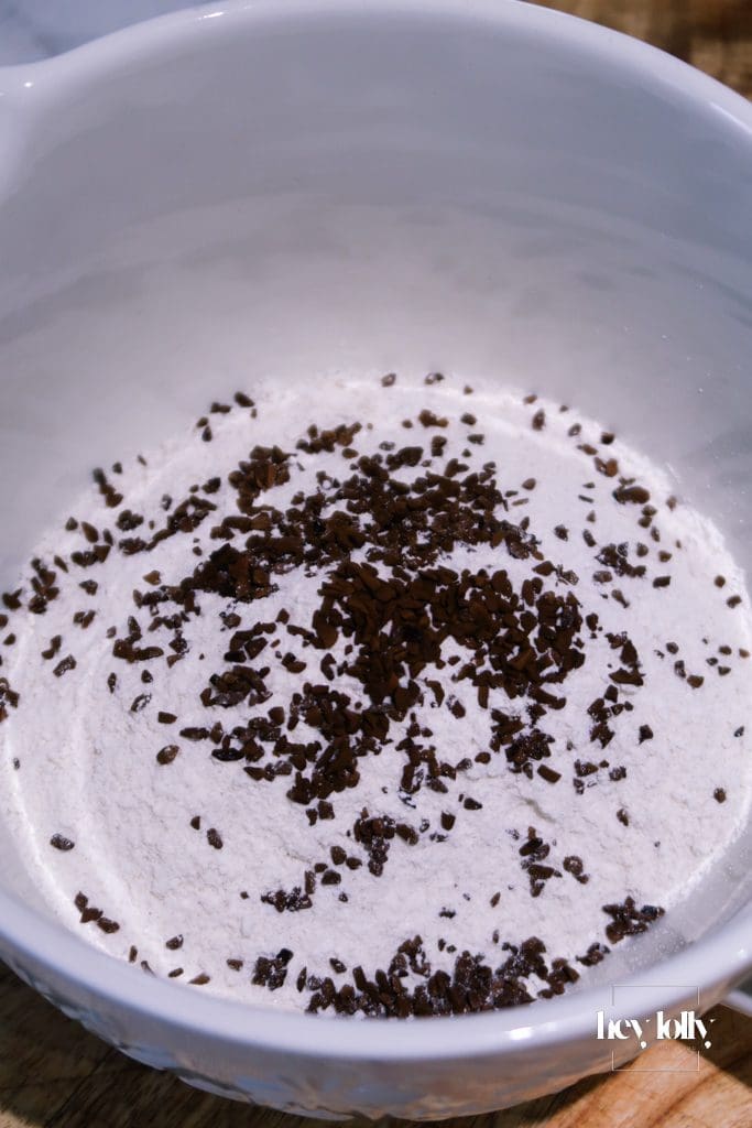 Flatlay of ingredients for pecan and coffee cake, including flour, sugar, coffee, eggs and pecans on a kitchen counter.