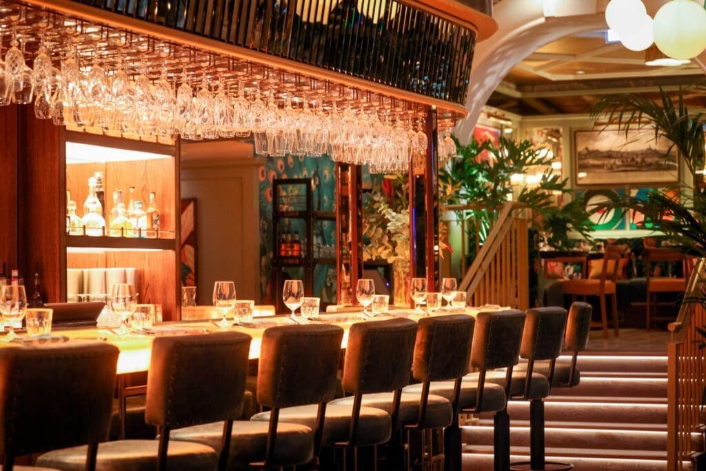 Interior of The Ivy Nottingham dining room with brass tables, velvet seating and artwork creating an elegant restaurant setting