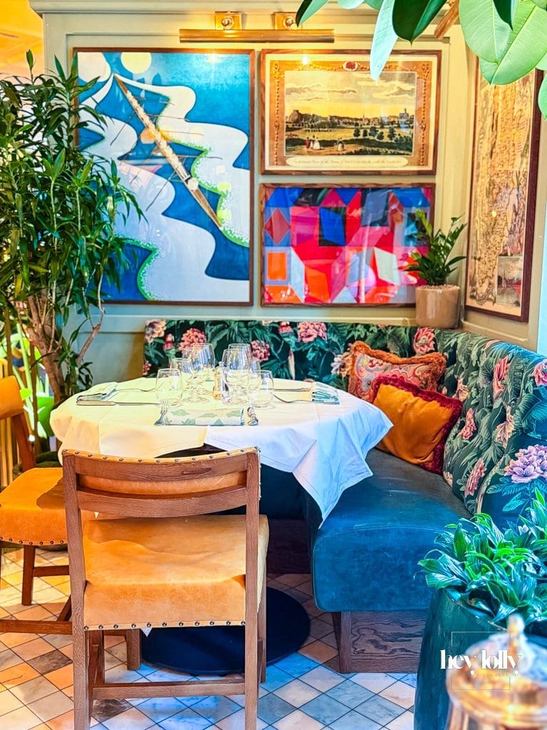 Interior of The Ivy Nottingham dining room with brass tables, velvet seating and artwork creating an elegant restaurant setting