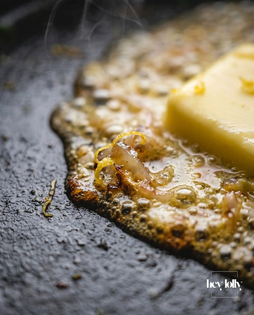 Lemon butter sauce with shallots and zest melting in pan