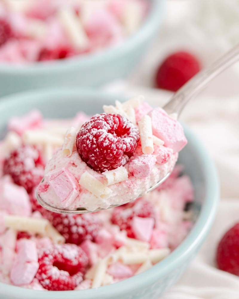 Finished raspberry whip topped with raspberries, white chocolate curls and crushed meringue